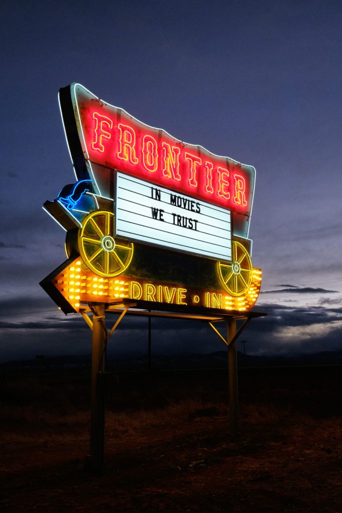 The Frontier Drive-Inn neon sign lit up with the night sky in the background.