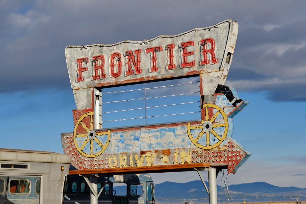 The old, derelict Frontier Drive Inn sign at midday