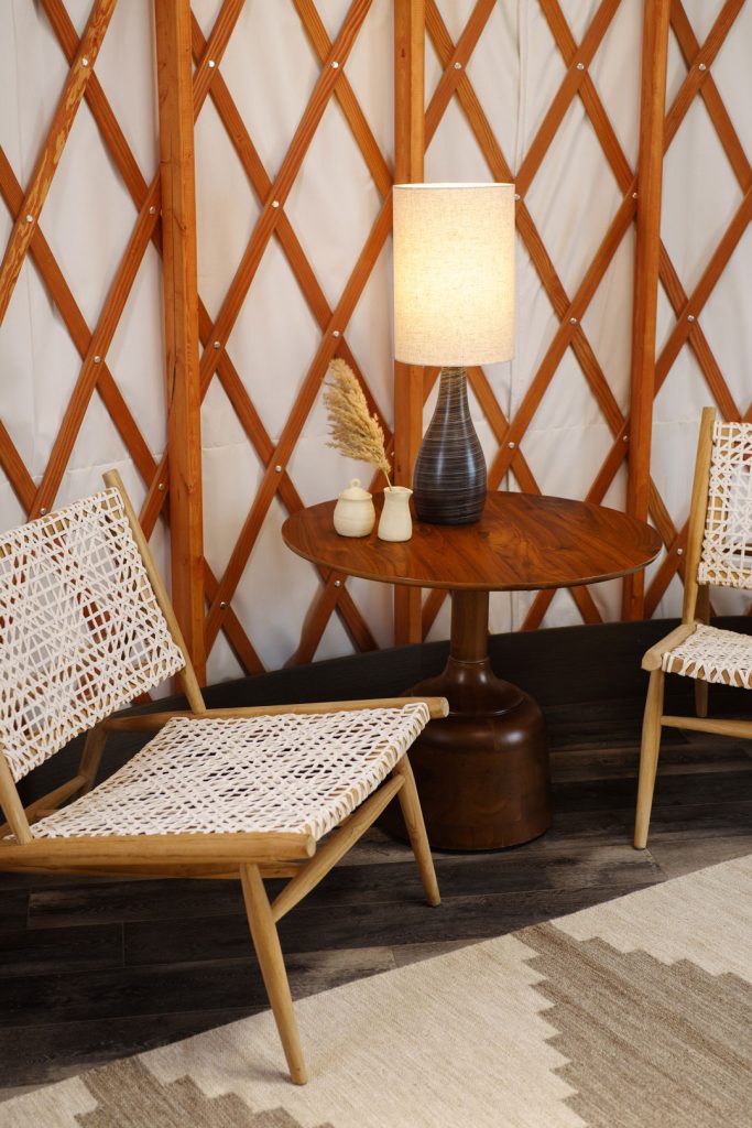 The sitting area of a yurt room with two woven chairs and a small table