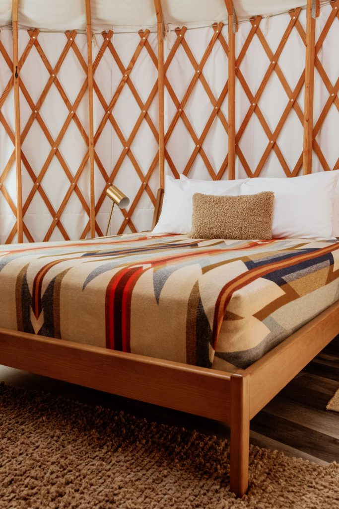 Interior view of a yurt with patterned bedding and a gold lamp